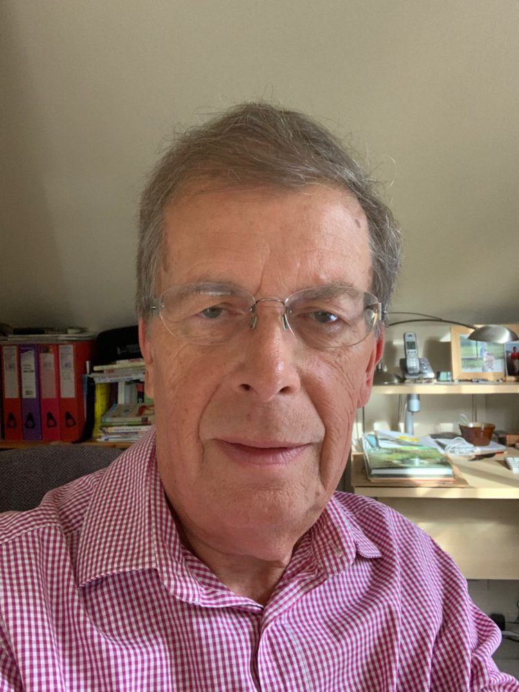 Photo of John Hartley wearing dark pink and white small check shirt.