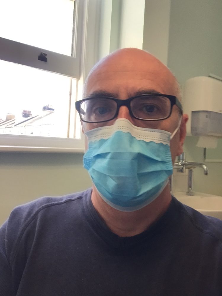 Photo of John Quin wearing blue surgical mask.